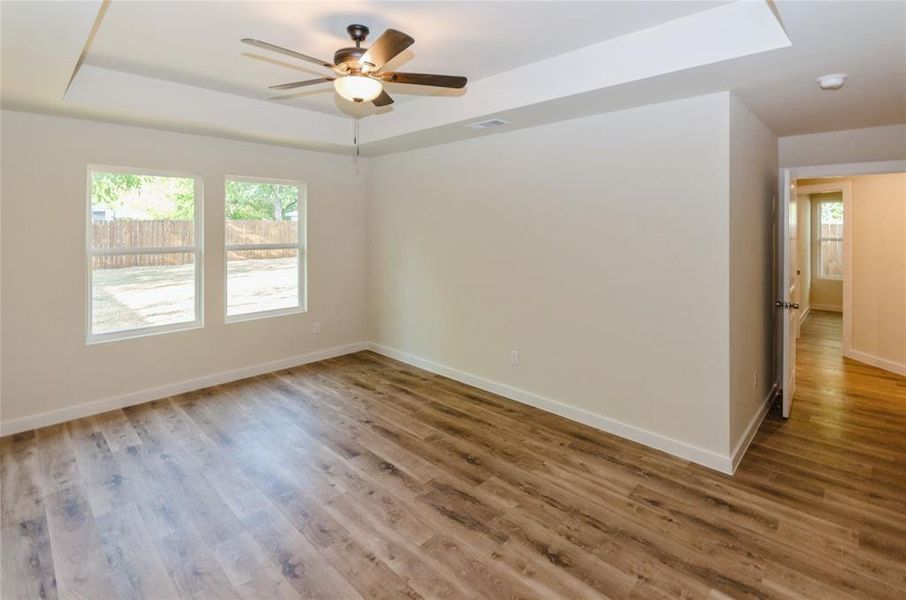 Unfurnished room with wood-type flooring, a tray ceiling, and ceiling fan