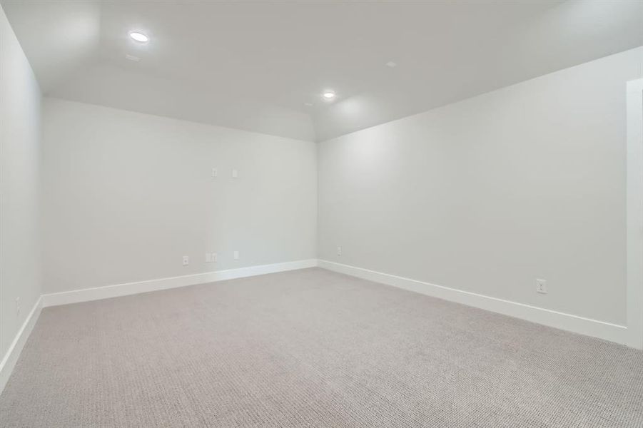 Empty room with vaulted ceiling and light carpet