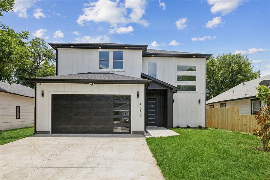 View of front of property featuring a garage and a front lawn