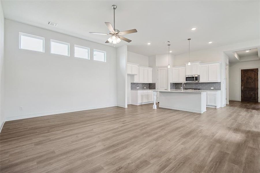 Unfurnished living room featuring light hardwood / wood-style floors, ceiling fan, and sink