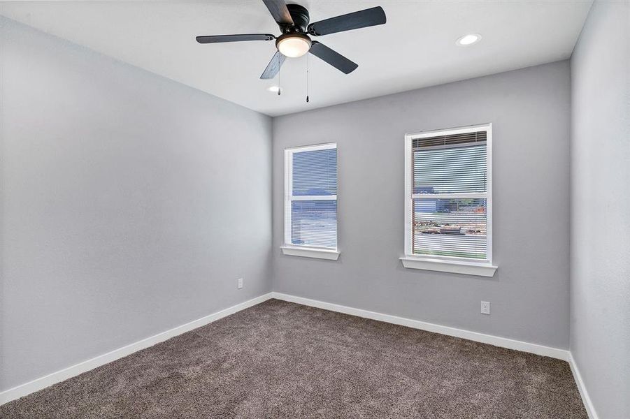 Carpeted empty room featuring ceiling fan