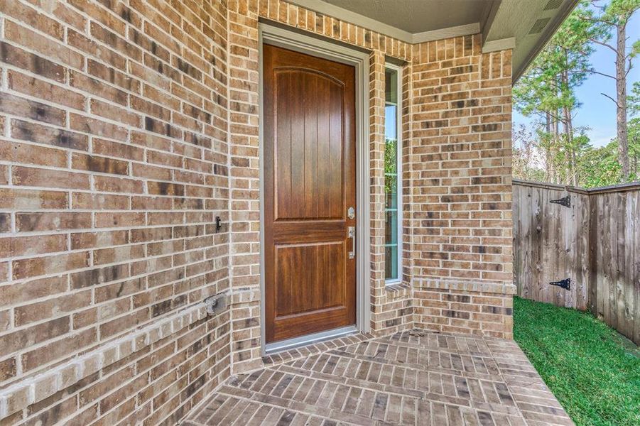 Convenient and cozy front porch features a beautifully stained carriage door entrance.