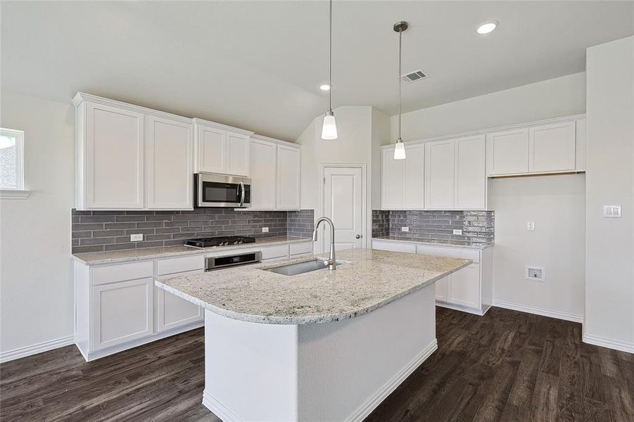 Kitchen featuring dark hardwood / wood-style flooring, stainless steel appliances, decorative light fixtures, backsplash, and sink