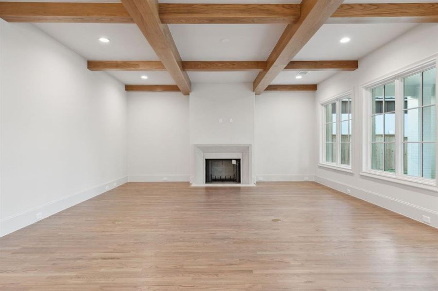 Unfurnished living room with beamed ceiling, light hardwood / wood-style flooring, and coffered ceiling
