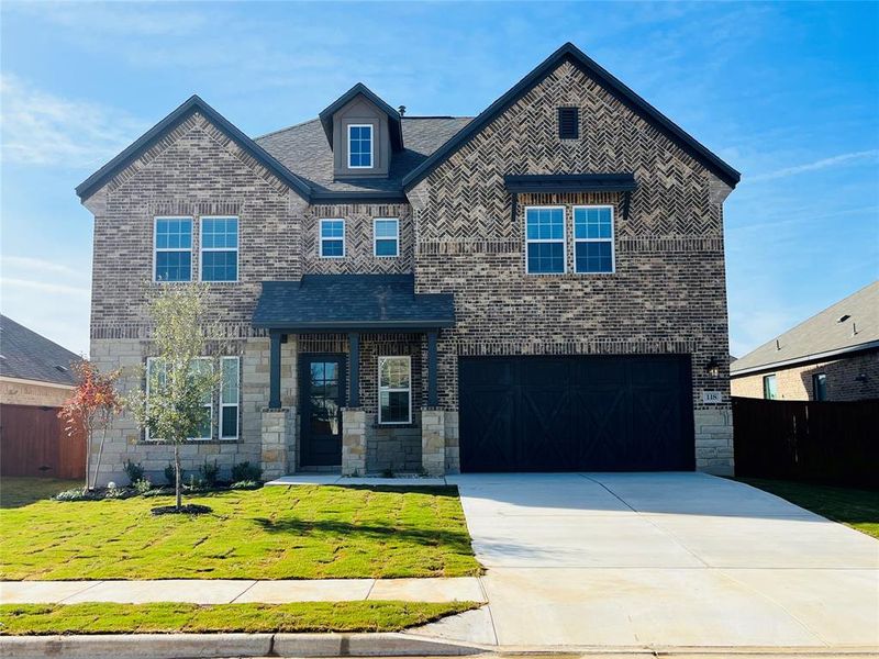 The Yale plan at The Colony is a beautiful two-story home with a long driveway, gorgeous cedar garage door, and lush front yard landscaping.