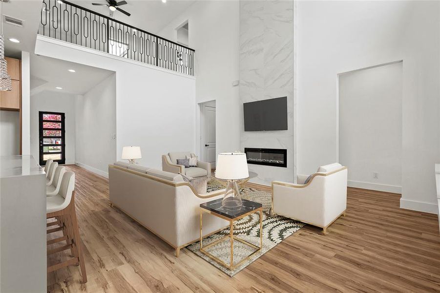 Living room featuring a towering ceiling, hardwood / wood-style flooring, a fireplace, and ceiling fan