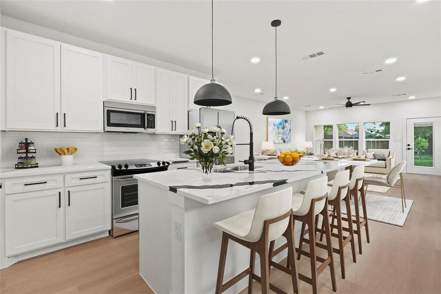 Kitchen featuring tasteful backsplash, pendant lighting, an island with sink, light hardwood / wood-style floors, and appliances with stainless steel finishes