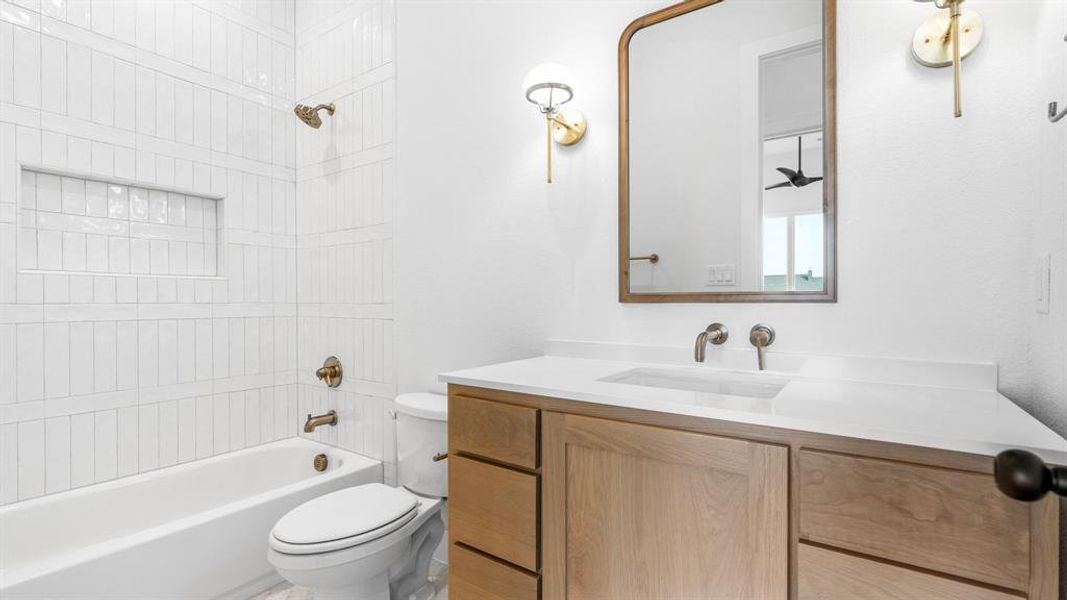 Full bathroom with tiled shower / bath, vanity, and toilet