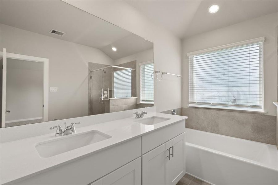 The Primary Bath Oasis features dual sinks with extended countertop, glass encased walk-in shower with tile surround, separate soaking tub and modern finishes throughout.