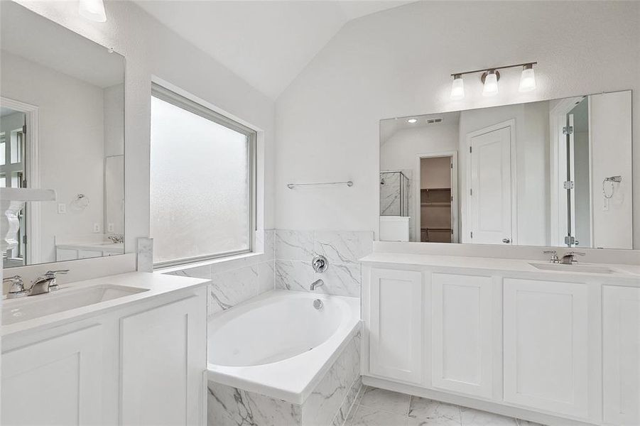 Bathroom with plenty of natural light, tile patterned floors, tiled bath, and vaulted ceiling