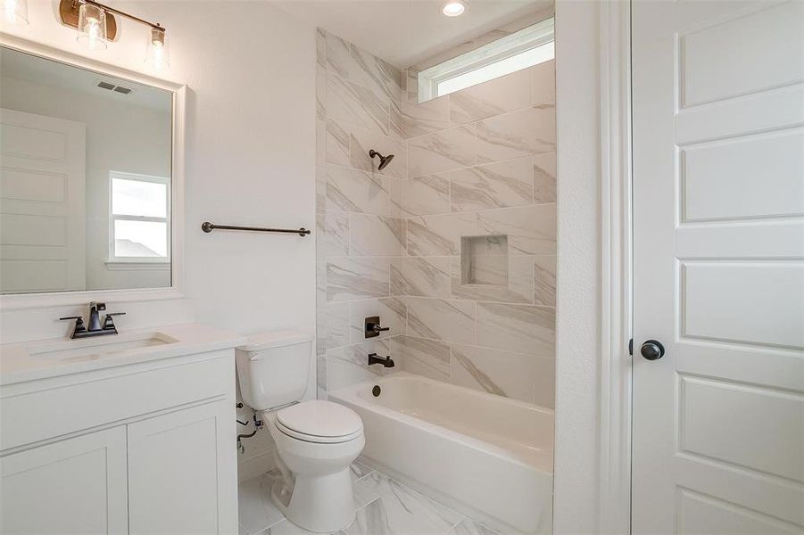 Full bathroom with vanity, tiled shower / bath combo, and toilet