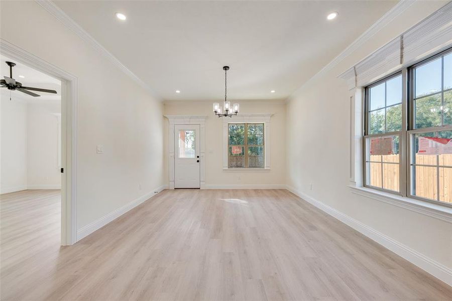 Spare room featuring ornamental molding, light hardwood / wood-style flooring, and ceiling fan with notable chandelier