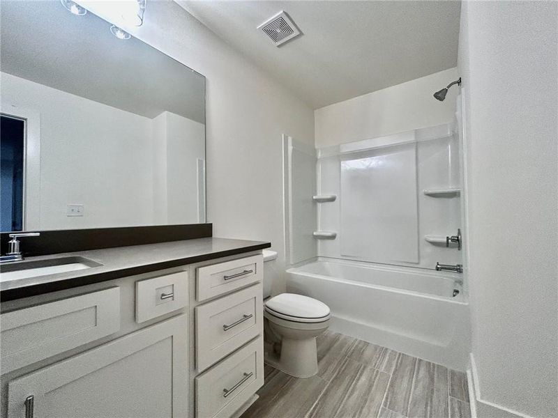 Full bathroom with tub / shower combination, toilet, tile flooring, and vanity