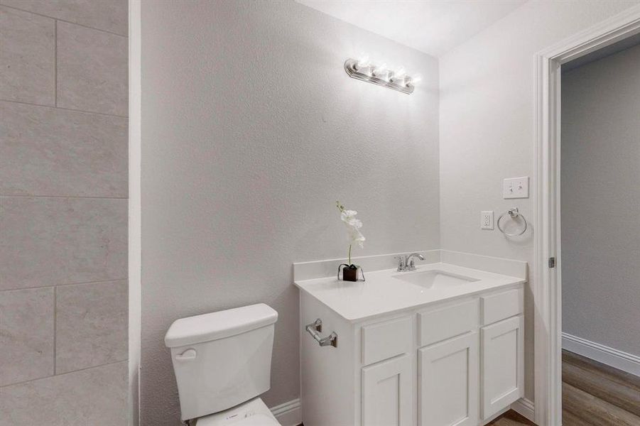 Bathroom featuring hardwood / wood-style flooring, vanity, and toilet