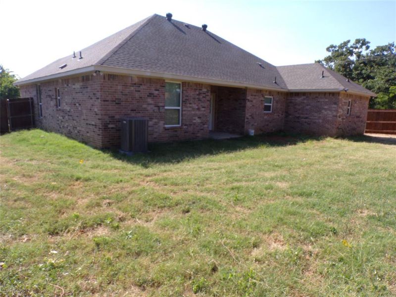 Back of property with a lawn and central AC unit