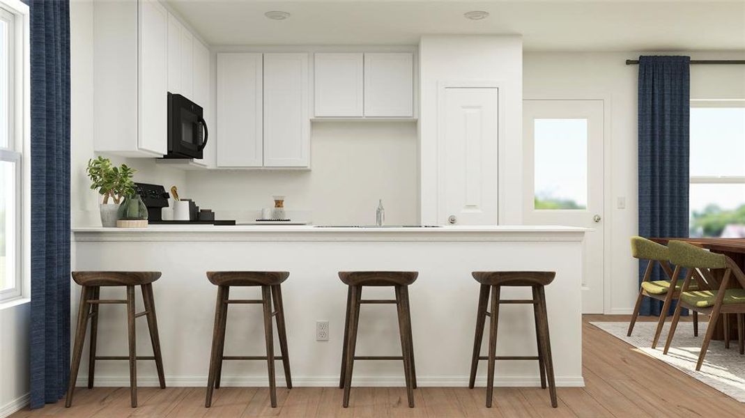Kitchen with range, sink, light wood-type flooring, a kitchen breakfast bar, and white cabinetry