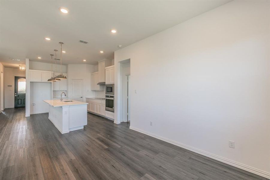 Kitchen featuring dark hardwood / wood-style floors, a kitchen island with sink, sink, and white cabinetry