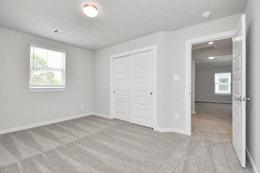 Secondary bedrooms showcase 5-panel doors adorned with modern hardware, large windows enhanced by privacy blinds, and spacious closets featuring sleek and contemporary finishes.