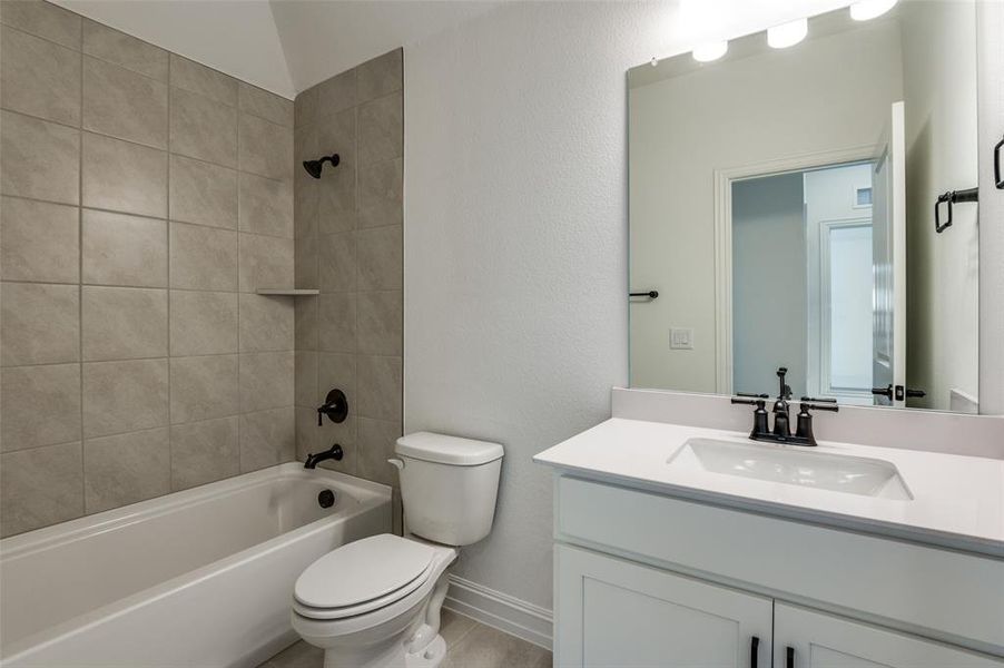 Full bathroom with vanity, tiled shower / bath combo, and toilet