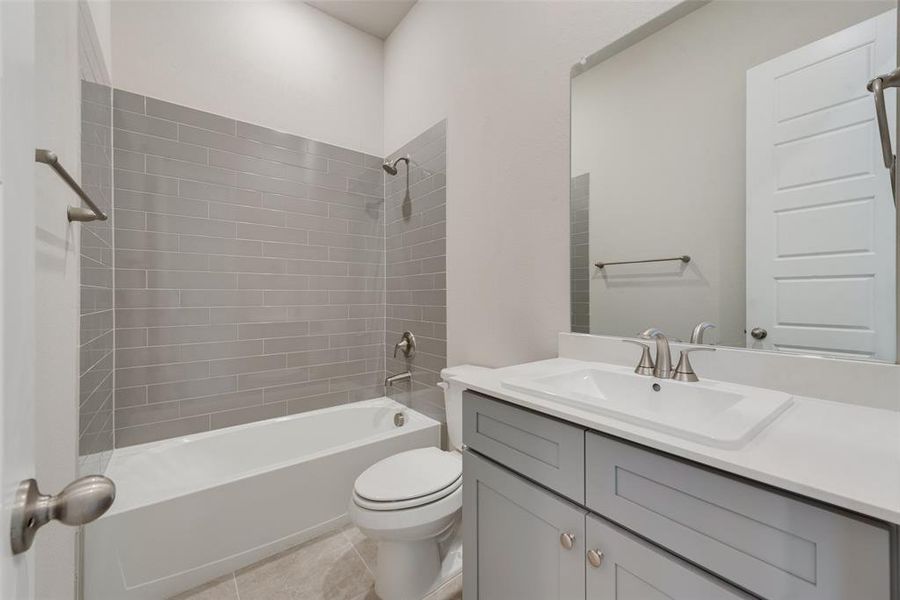 Full bathroom with tile patterned floors, vanity, tiled shower / bath, and toilet
