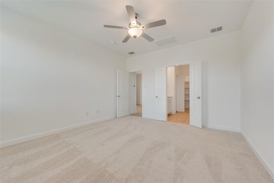 Unfurnished bedroom with ceiling fan, light colored carpet, a closet, and a spacious closet