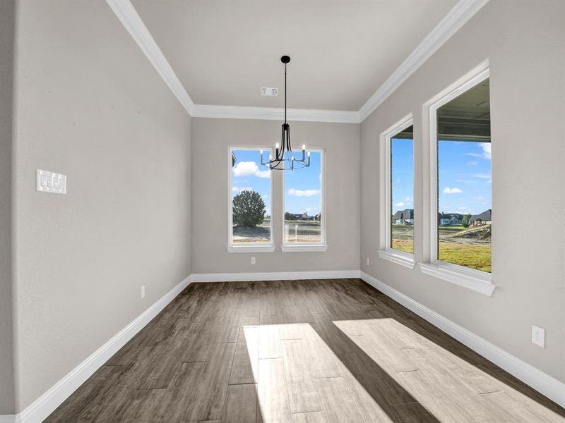 Unfurnished dining area featuring dark wood-type flooring, a notable chandelier, and ornamental molding