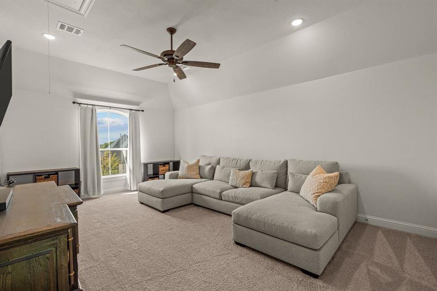 Living room featuring vaulted ceiling, carpet floors, and ceiling fan