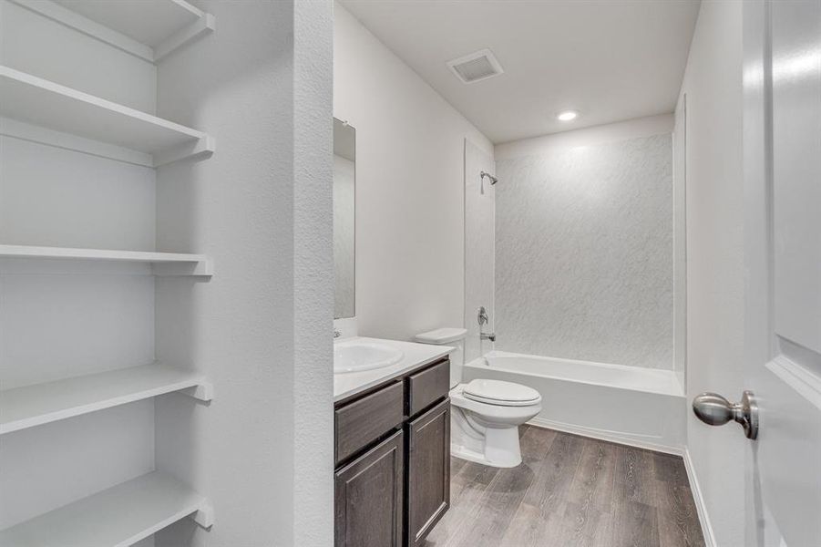 Full bathroom with bathtub / shower combination, wood-type flooring, vanity, and toilet