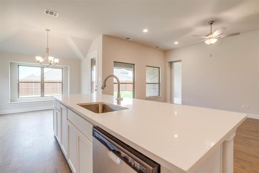 Kitchen featuring a wealth of natural light, stainless steel dishwasher, sink, and a kitchen island with sink