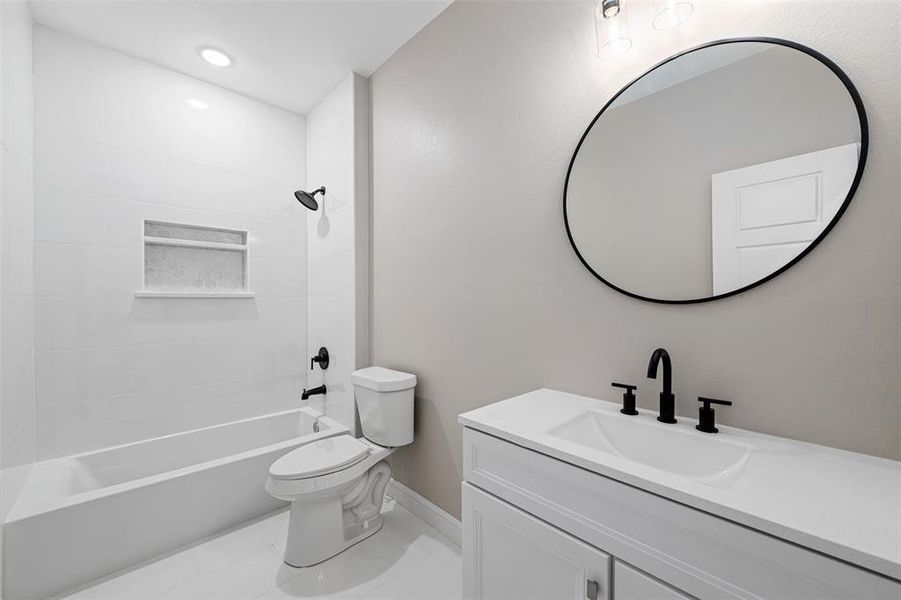 Full bathroom featuring toilet, tiled shower / bath combo, and vanity