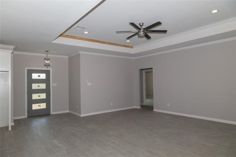 Spacious living room with upgraded front door.  Tray ceiling and modern ceiling fan.