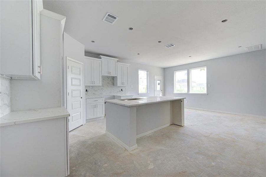 The kitchen island, with its generous surface area, serves as both a workspace and a gathering spot for family and friends. With contemporary finishes and ample storage, this kitchen is designed for both function and style. **This image is from another Saratoga Home - Athena floorplan.**