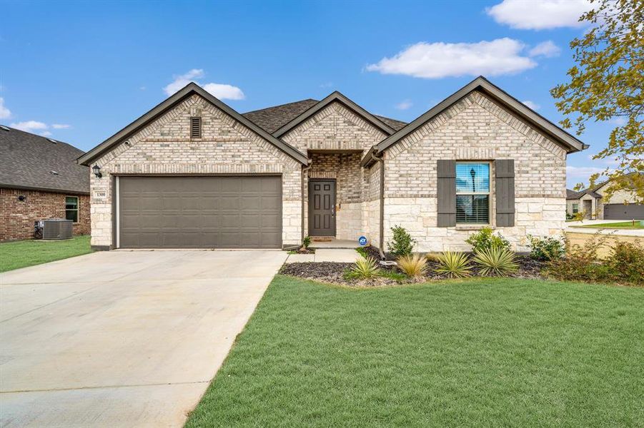 View of front of home with central air condition unit, a front lawn, and a garage