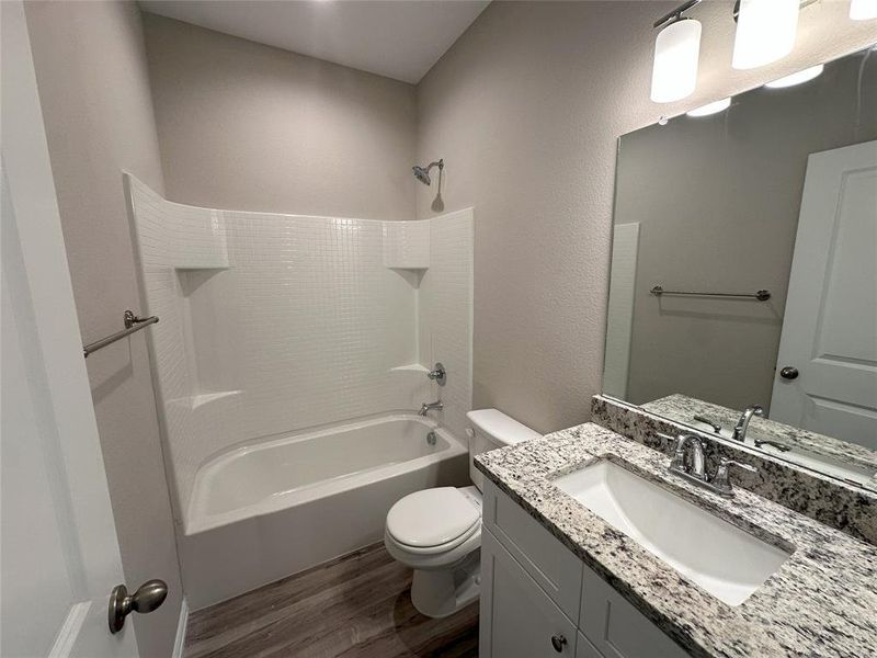 Full bathroom with hardwood / wood-style floors, toilet, bathing tub / shower combination, and vanity