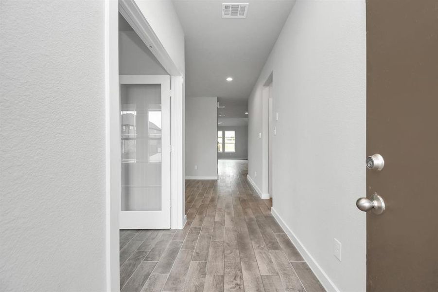 The majestic entryway allures with its high ceilings, embellished with sophisticated wood-look tile flooring and sleek oversized baseboards. Sample photo, actual color and selections can vary.