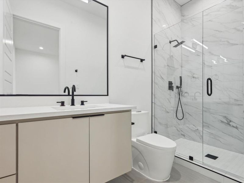Bathroom featuring a shower with door, tile flooring, vanity, and toilet