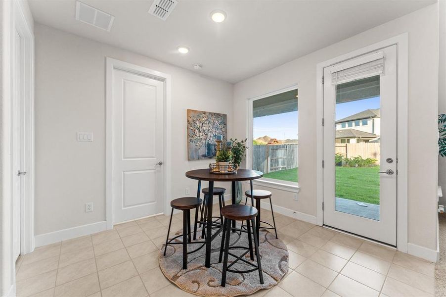 The breakfast area is bathed in natural light from a wide window, offering a pleasant view of the backyard. Its easy access makes it convenient for enjoying meals indoors while staying connected to outdoor activities and gatherings.