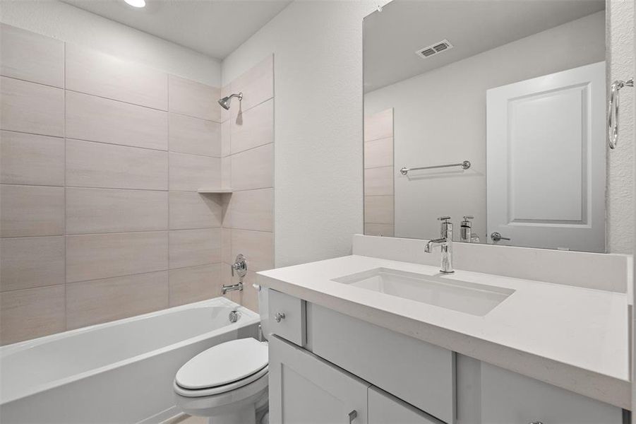 Full bathroom with tiled shower / bath combo, vanity, and toilet