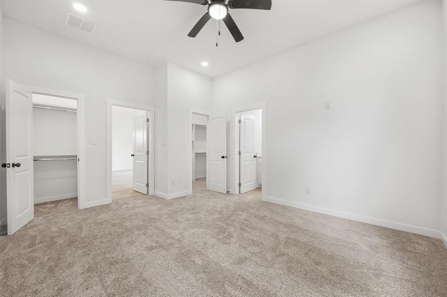 Unfurnished bedroom featuring a spacious closet, light carpet, ceiling fan, and a closet