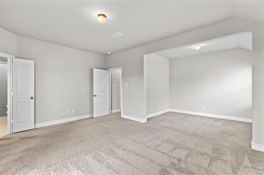 Carpeted spare room featuring vaulted ceiling