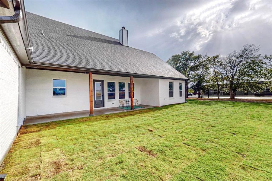 Rear view of house with a lawn and a patio area