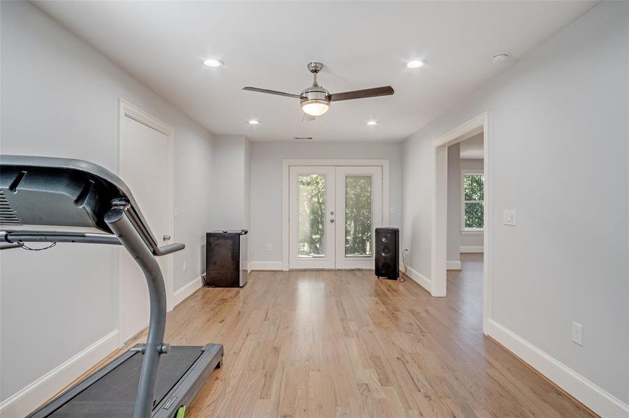 Workout room with light wood-type flooring, ceiling fan, and french doors