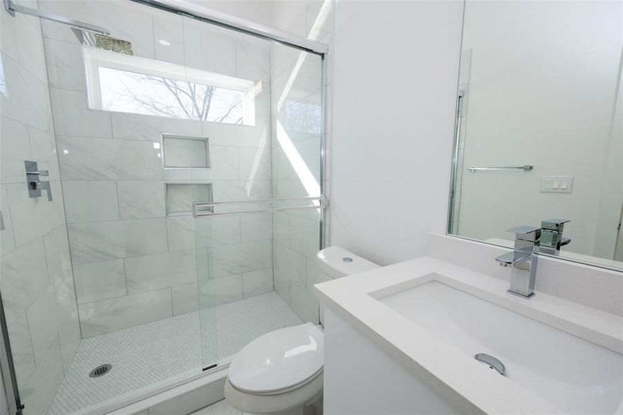 Bathroom with vanity with extensive cabinet space, an enclosed shower, and toilet