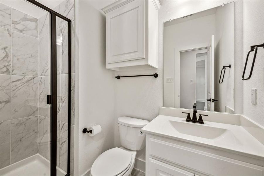 Bathroom featuring a shower with door, vanity, and toilet