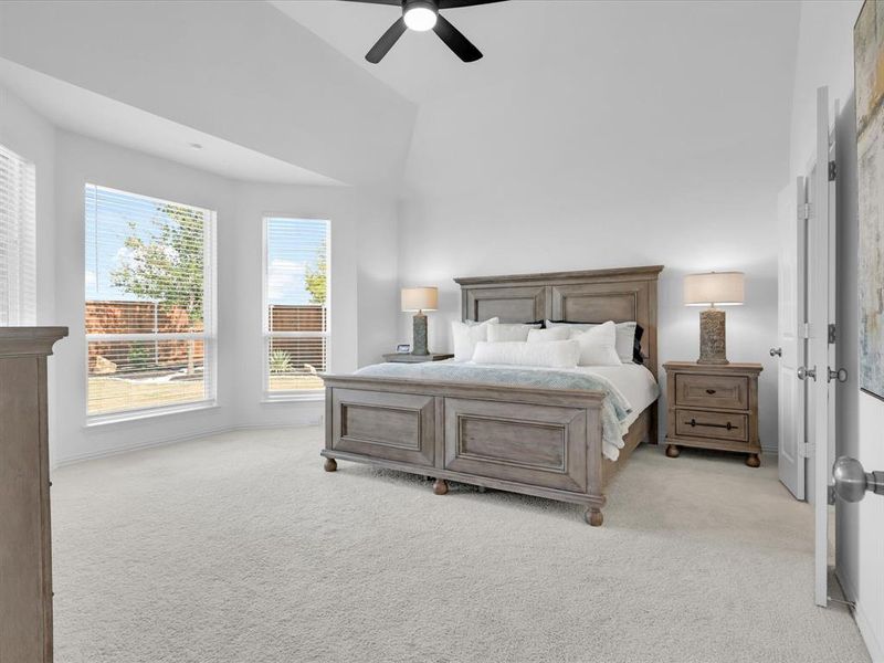 Bedroom featuring multiple windows, light carpet, ceiling fan, and lofted ceiling
