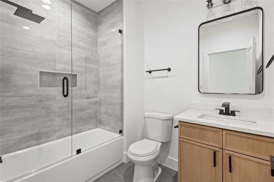 Full bathroom with combined bath / shower with glass door, toilet, tile floors, and large vanity