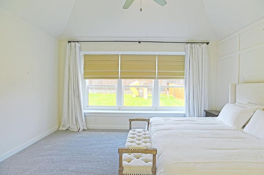 Bedroom with ceiling fan, vaulted ceiling, carpet floors, and multiple windows