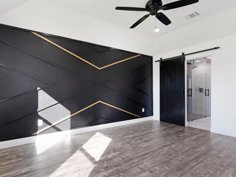 Empty room with ceiling fan, hardwood / wood-style flooring, and a barn door