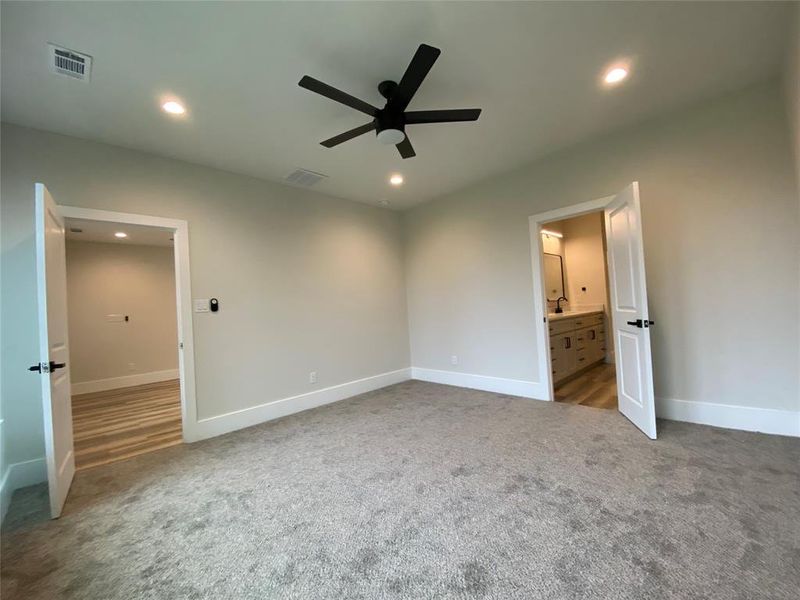 Unfurnished bedroom featuring carpet, ceiling fan, and ensuite bath