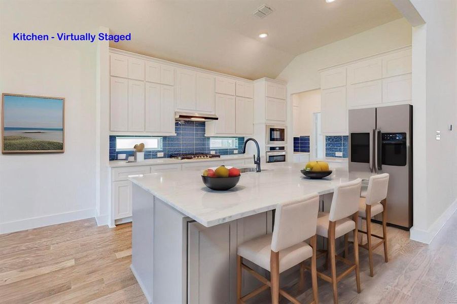 Kitchen featuring appliances with stainless steel finishes, light hardwood / wood-style floors, backsplash, an island with sink, and wall chimney exhaust hood